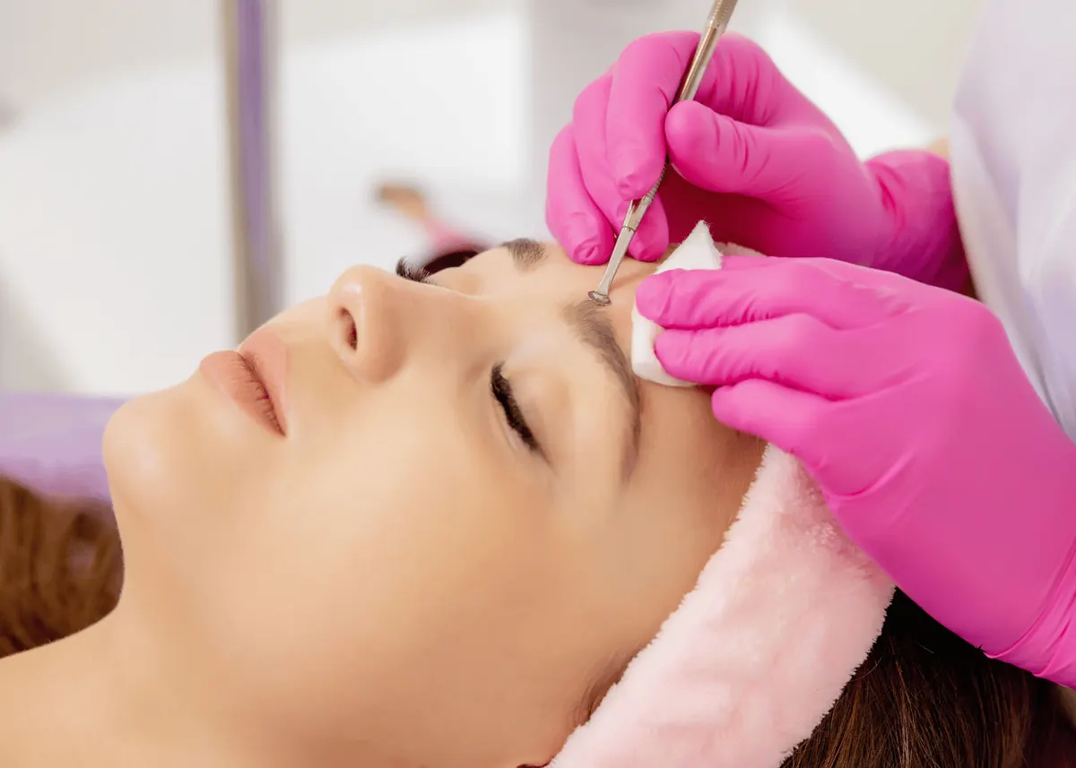 Licensed esthetician performing professional acne extractions during a treatment session