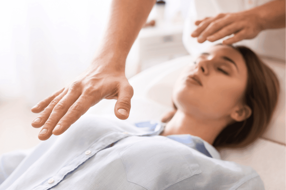 Hands of a Reiki Master over a body