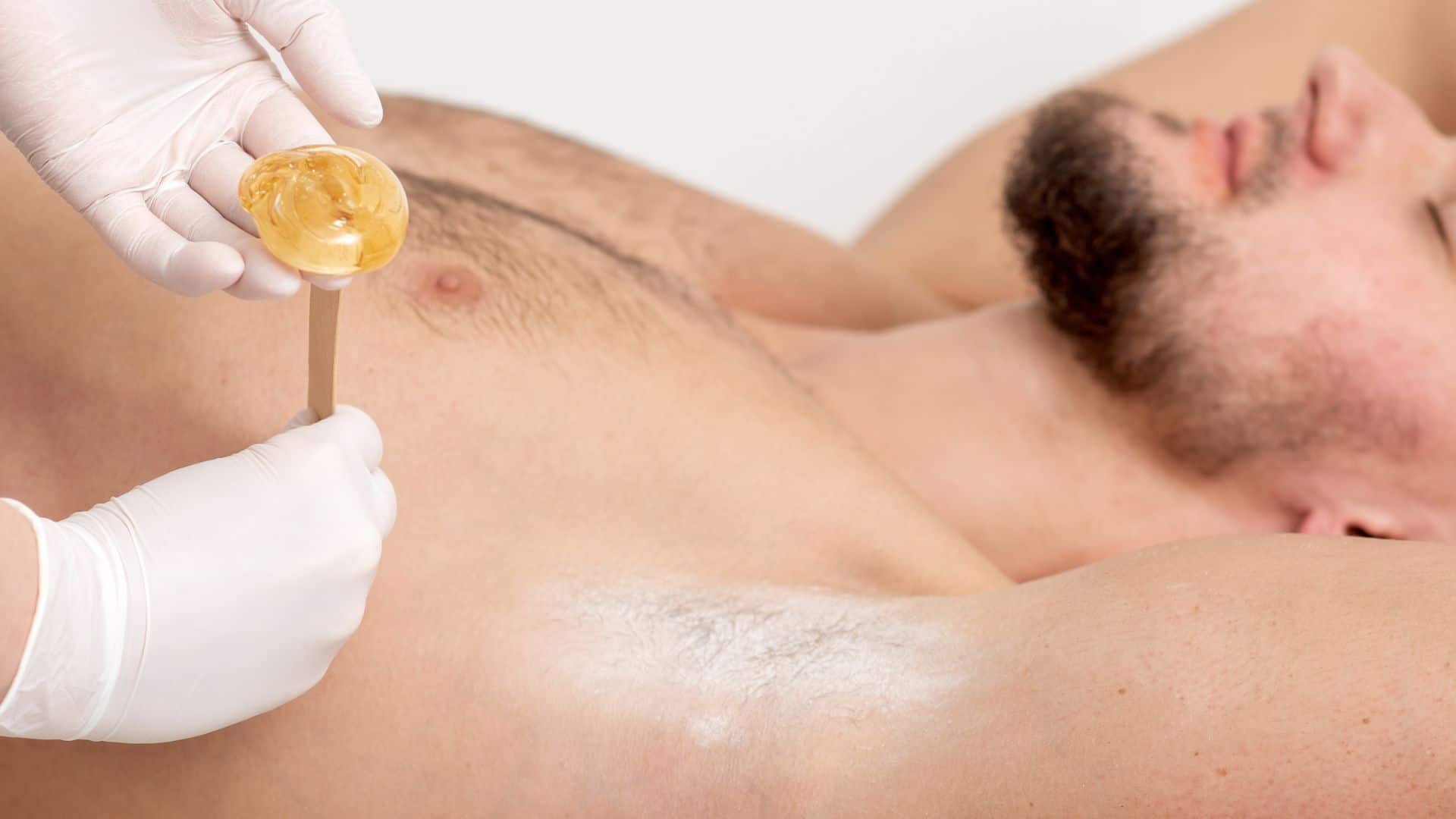 spa staff applying waxing cream to man on relaxing man